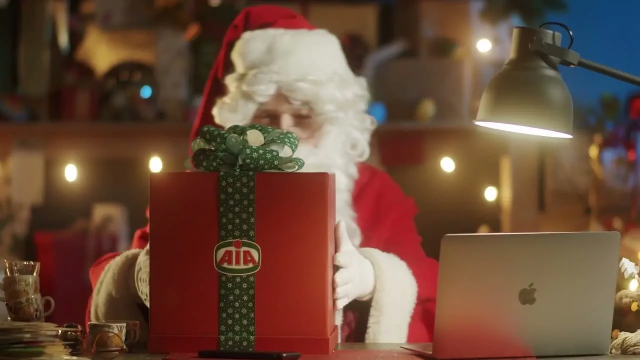 Babbo Natale con un regalo AIA e un portatile, da un film di Natale Fornace